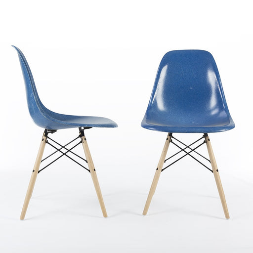 View of pair of blue Eames DSW dining side chairs, one from the right, one from the front