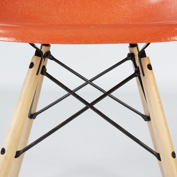 Close up view of base on orange Eames DSW dining side chair