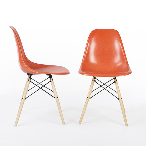 View of pair of orange Eames DSW dining side chairs, one from right side, one from front